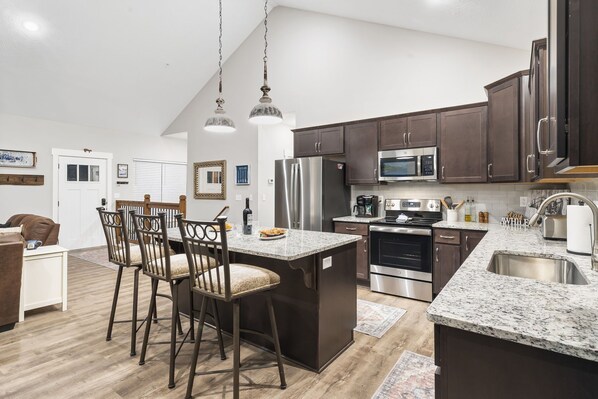 A modern kitchen with dark wooden cabinets, stainless steel appliances, and a granite countertop. - Lake View Condo with Private Hot Tub, $400 Free Daily Tickets & Unique Layout (Kimberling City)