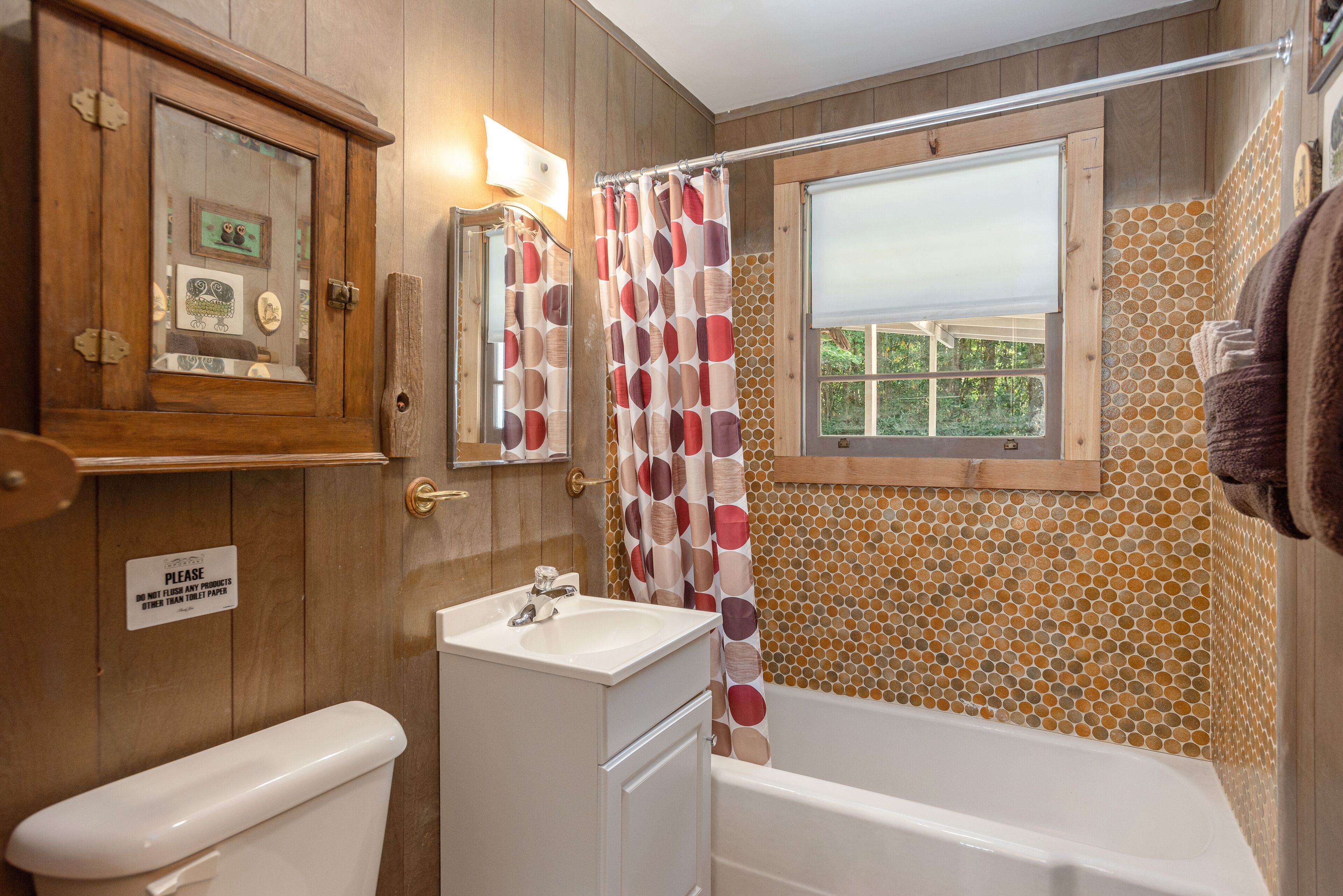Een badkamer met een houten kast, een toilet, een wastafel en een bad.
