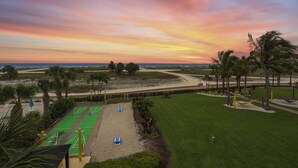 Ein Golfplatz mit grünem Rasen, Sandbunkern und einem Sonnenuntergangshimmel.