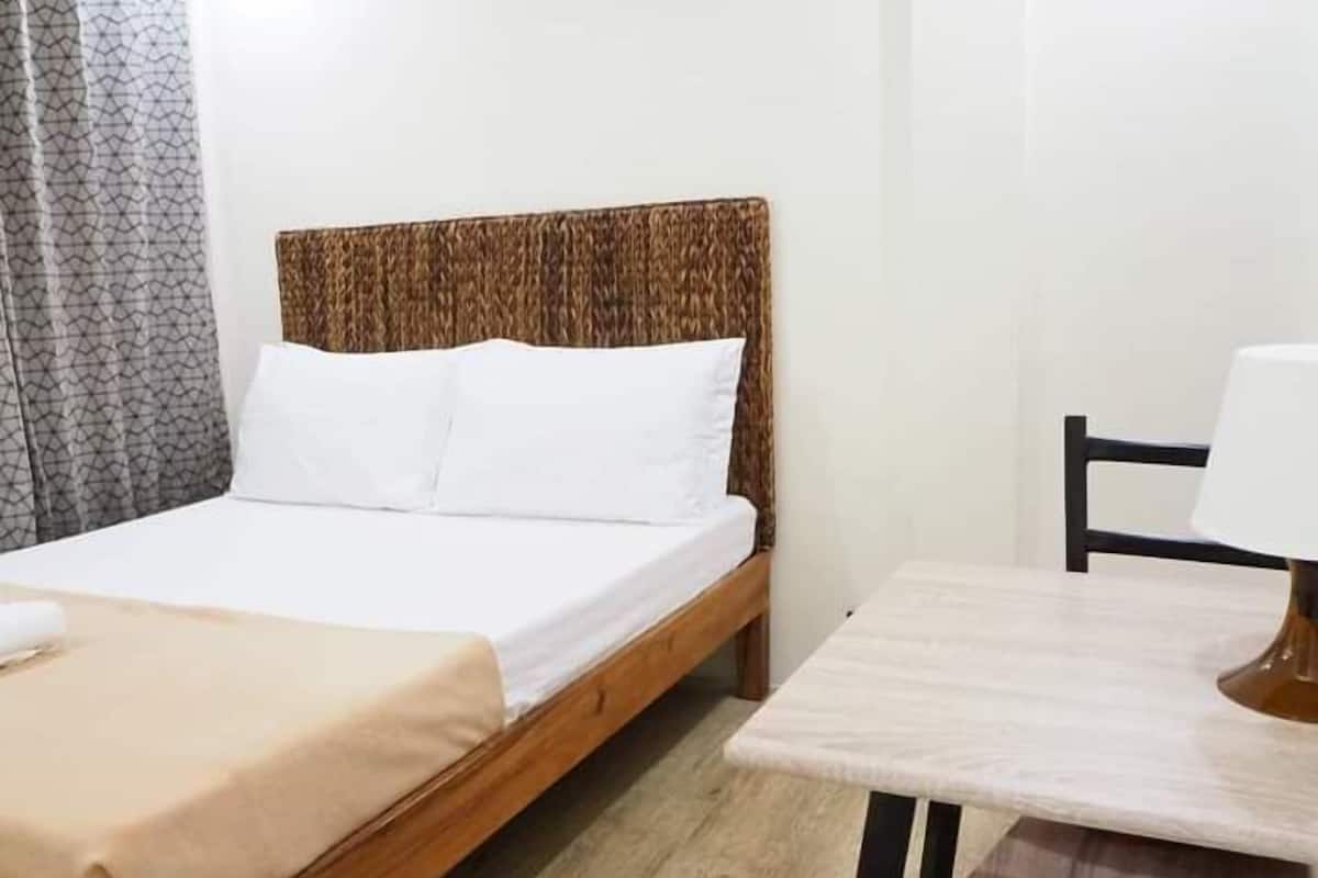 A single bed with a wooden headboard, a bedside table with a lamp, and a chair.