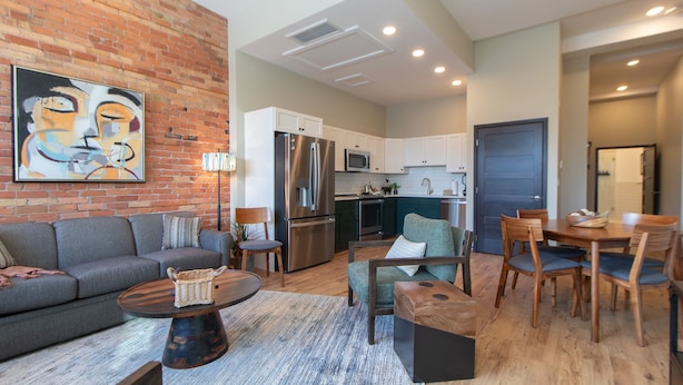 A modern living room with a sofa, coffee table, and a dining area with chairs and a table.
