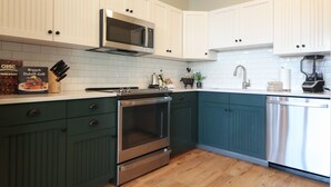 A kitchen with white upper cabinets, a microwave, a stove, and a dishwasher.