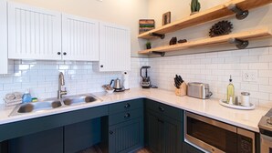 A modern kitchen with white cabinets, a sink, a toaster, and a blender. - Luxury Craft District Suites | Unit 102 (Duluth)