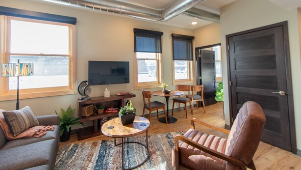 Un salon moderne comprenant un canapé, une table basse, un téléviseur et un coin repas avec des chaises et une table.