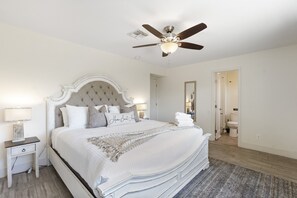 A bedroom with a large bed, a ceiling fan, a nightstand, and a bedside table. - Fairmount Inn (Scottsdale)