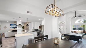 A spacious living area with a pool table, a dining table, and a kitchen in the background. - Casa Yucca 1 (Chandler)