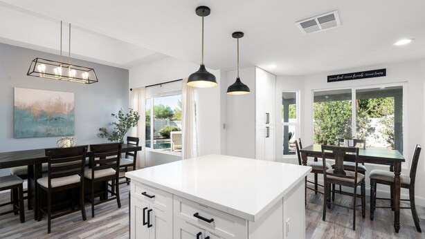 A modern kitchen with white cabinetry, a central island, and pendant lighting. - Casa Yucca 1 (Chandler)