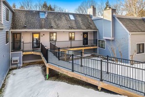 A two-story house with a covered patio and a fenced deck. - New Ski Mtn Condo, Walk to Ski Hill - Kingswood 6C (Quechee)