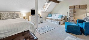 Une chambre à coucher comprenant un lit, un canapé, une armoire et une petite table avec une lampe.