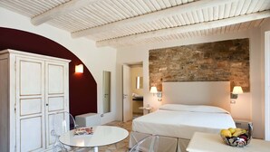 Ein Hotelzimmer mit einem Bett, einem kleinen Tisch, einem Stuhl, einem Kleiderschrank und einer Steinwand.