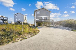 Une maison de plage à deux étages, dotée d’un balcon et d’un porche abrité.