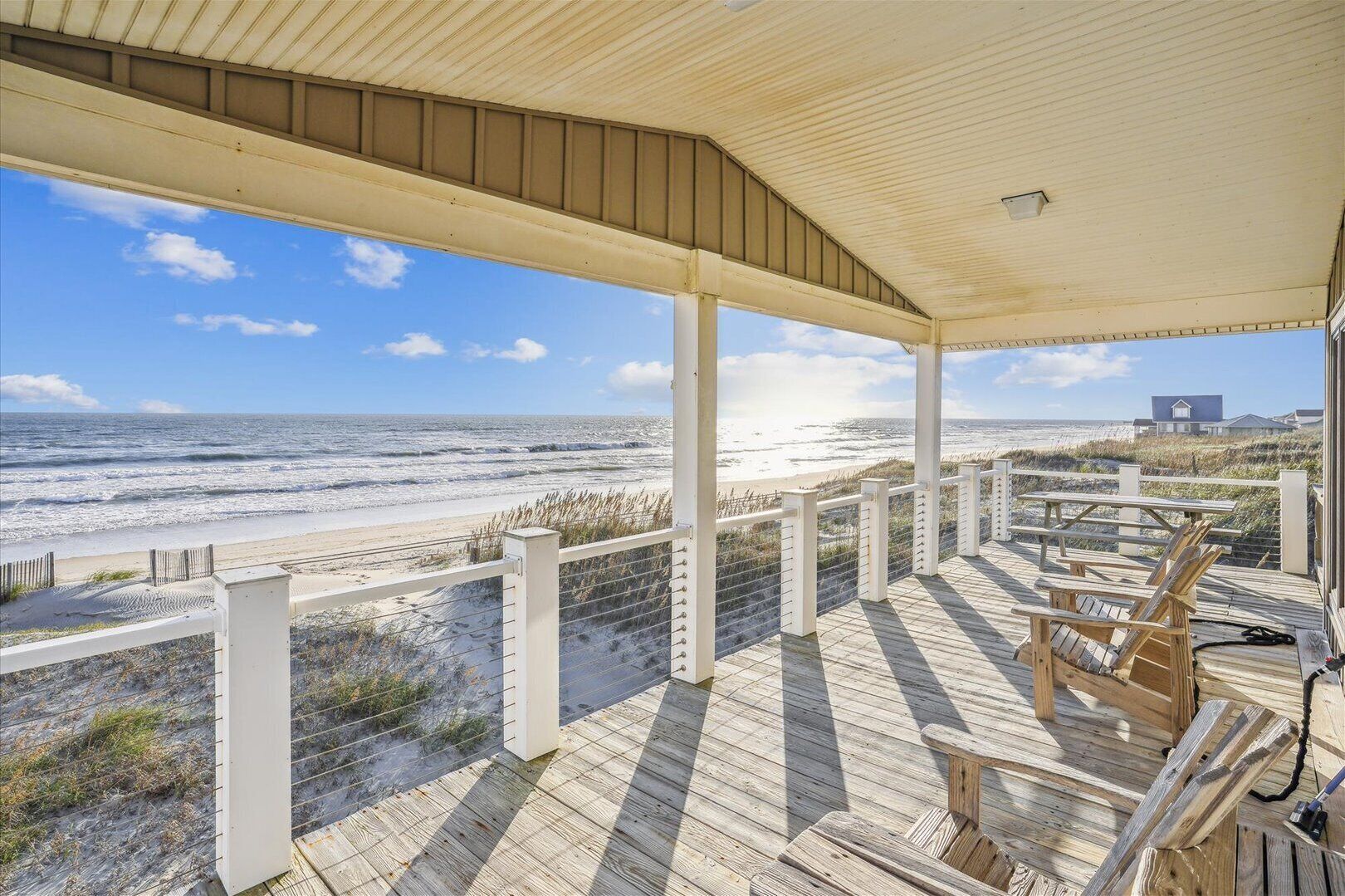 A wooden deck with chairs overlooking a beach.