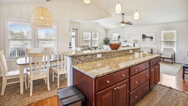A spacious kitchen with a large island, pendant lights, and a ceiling fan.