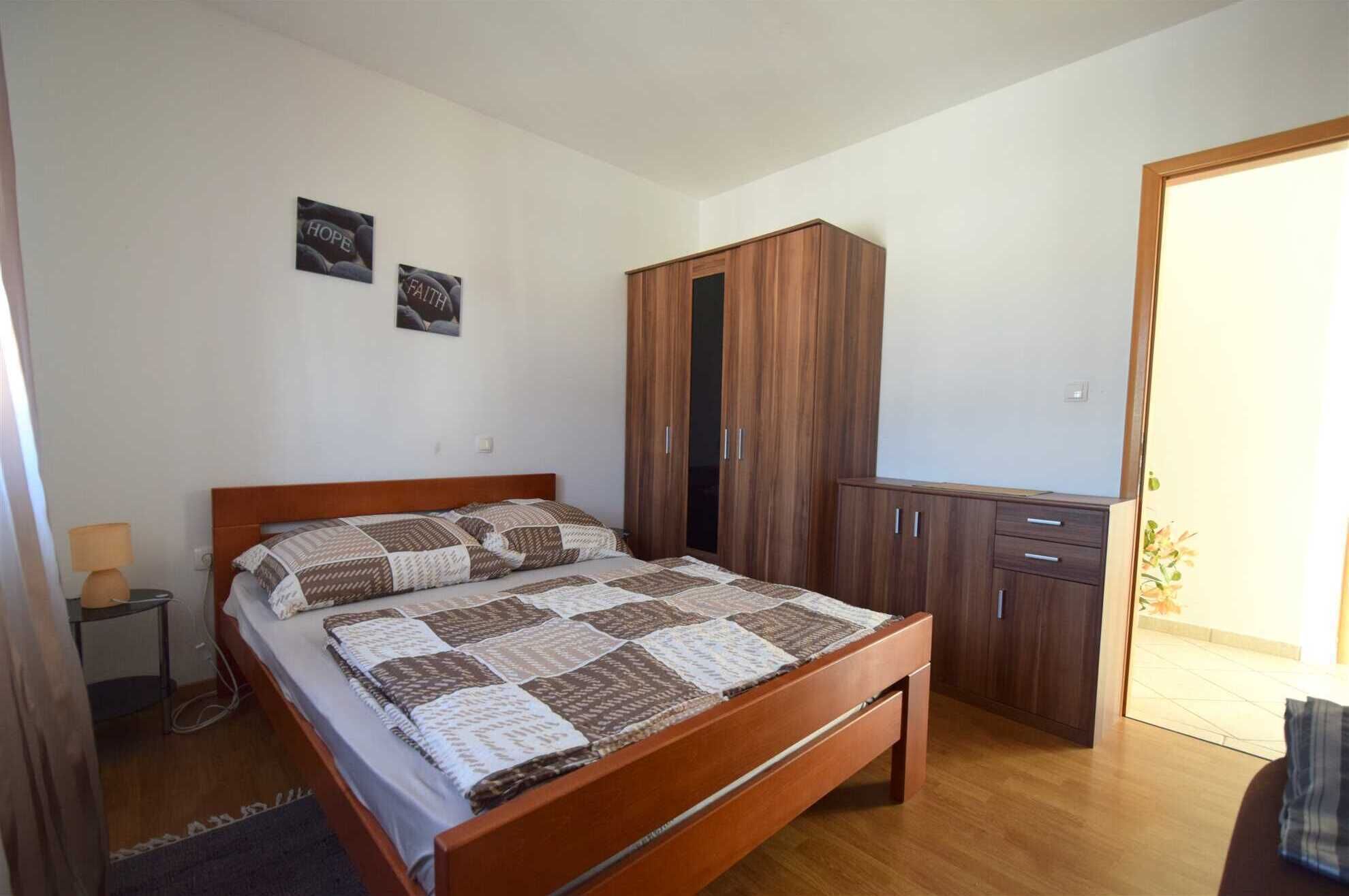 Un dormitorio con una cama de madera, un armario y dos cuadros en la pared.