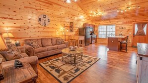 A cozy log cabin interior with a living room, kitchen, and dining area.