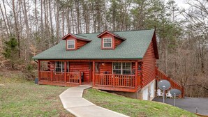 A log cabin with a porch, a covered deck, and satellite dishes.