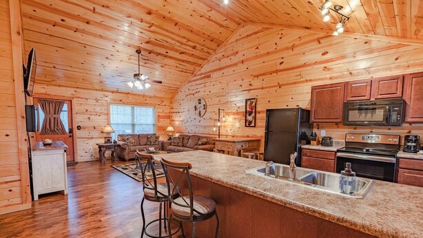 A cozy cabin interior with a wooden interior, a kitchen with modern appliances, and a dining area with bar stools.
