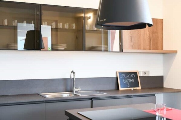 A modern kitchen with a black pendant light, a stainless steel sink, and a chalkboard sign that reads "CELLAGIO DREAMS". - Bellagio Dreams, Appartamento di Lusso (Bellagio)