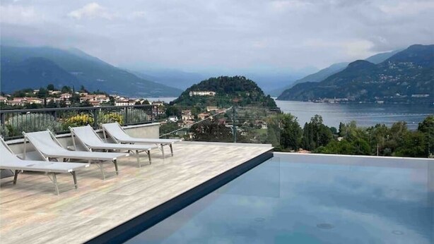 Une piscine à débordement avec des chaises longues et une vue sur un lac et des montagnes.