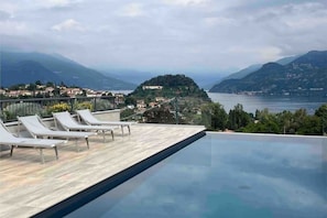 An infinity pool with lounge chairs and a view of a lake and mountains. - Bellagio Dreams, Appartamento di Lusso (Bellagio)