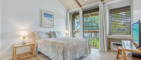 A bedroom with a bed, a nightstand, a desk, a chair, a window with blinds, and a ceiling fan.