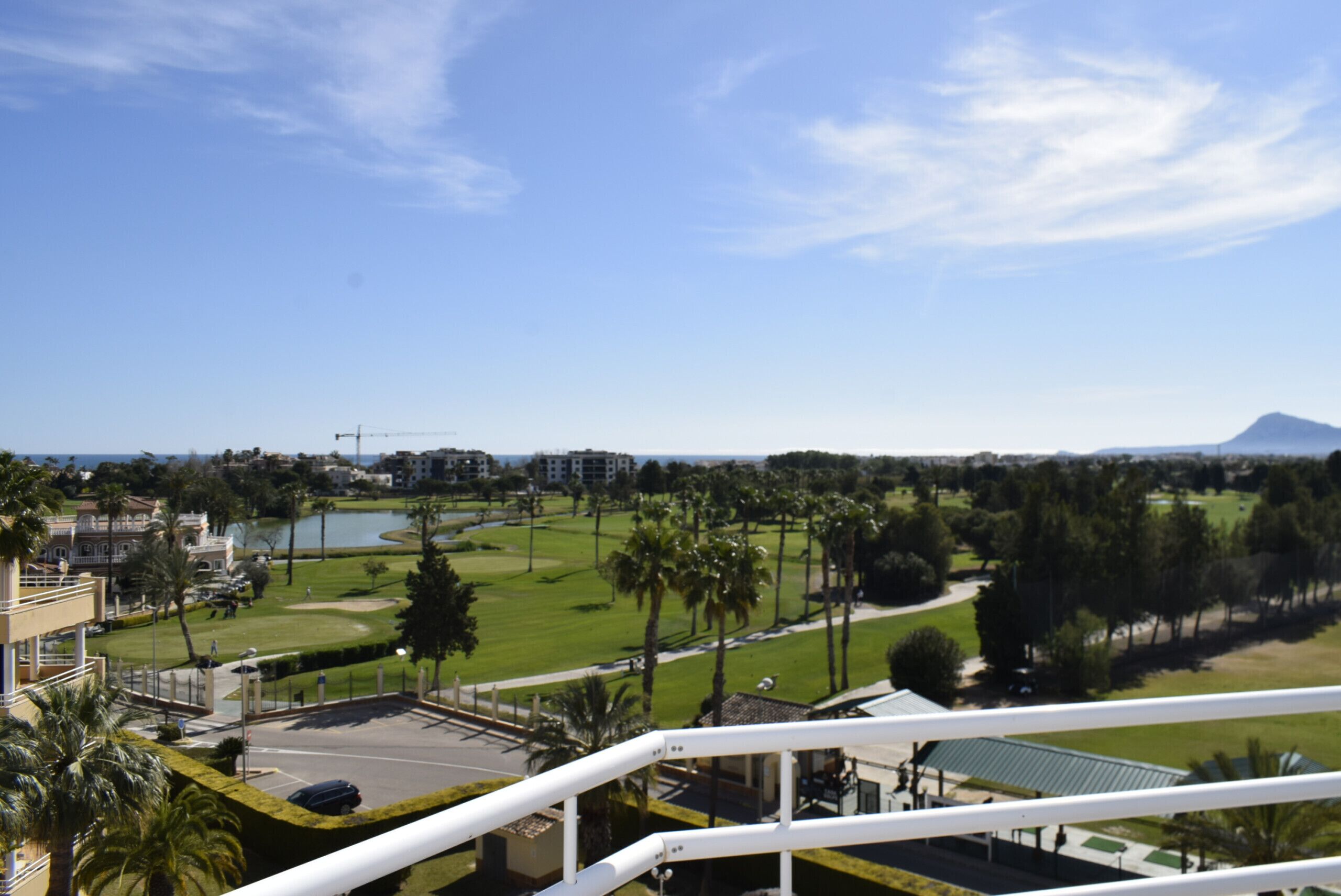 A view from a balcony overlooking a golf course with a mountain in the background.