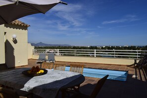 A terrace with a table set for dining, a pool, and a view of the landscape. - Anacasa Atico MET Oliva Nova Golf AT1403 (Oliva)