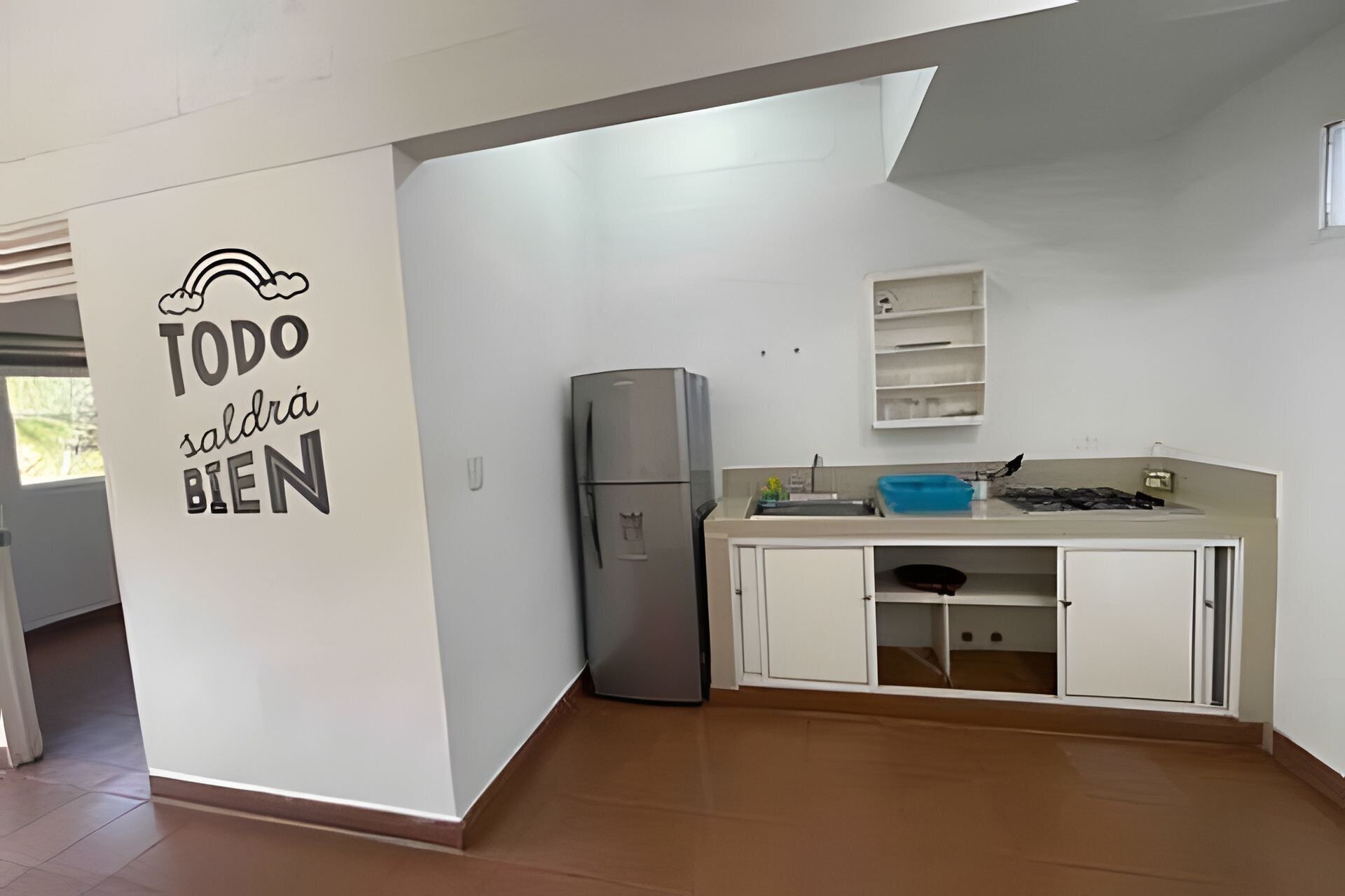 Une cuisine équipée d’un réfrigérateur, de placards et d’un mur sur lequel est accroché un panneau.