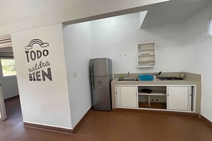 A kitchen with a refrigerator, cabinets, and a wall with a sign. - Our Home San Antonio (Cali)