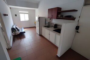 A compact kitchen with white cabinets, a built-in oven, and a window providing natural light. - Our Home San Antonio (Cali)