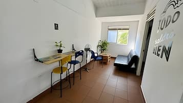 Una habitación con una mesa de comedor, sillas, un sofá, un ventanal y una pared con un letrero.
