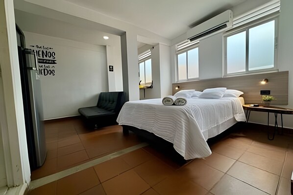 A bedroom with a bed, a desk, a chair, and a small table. - Our Home San Antonio (Cali)