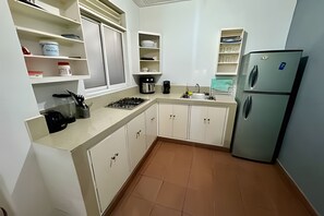 A compact kitchen with a gas stove, a sink, and a refrigerator. - Our Home San Antonio (Cali)