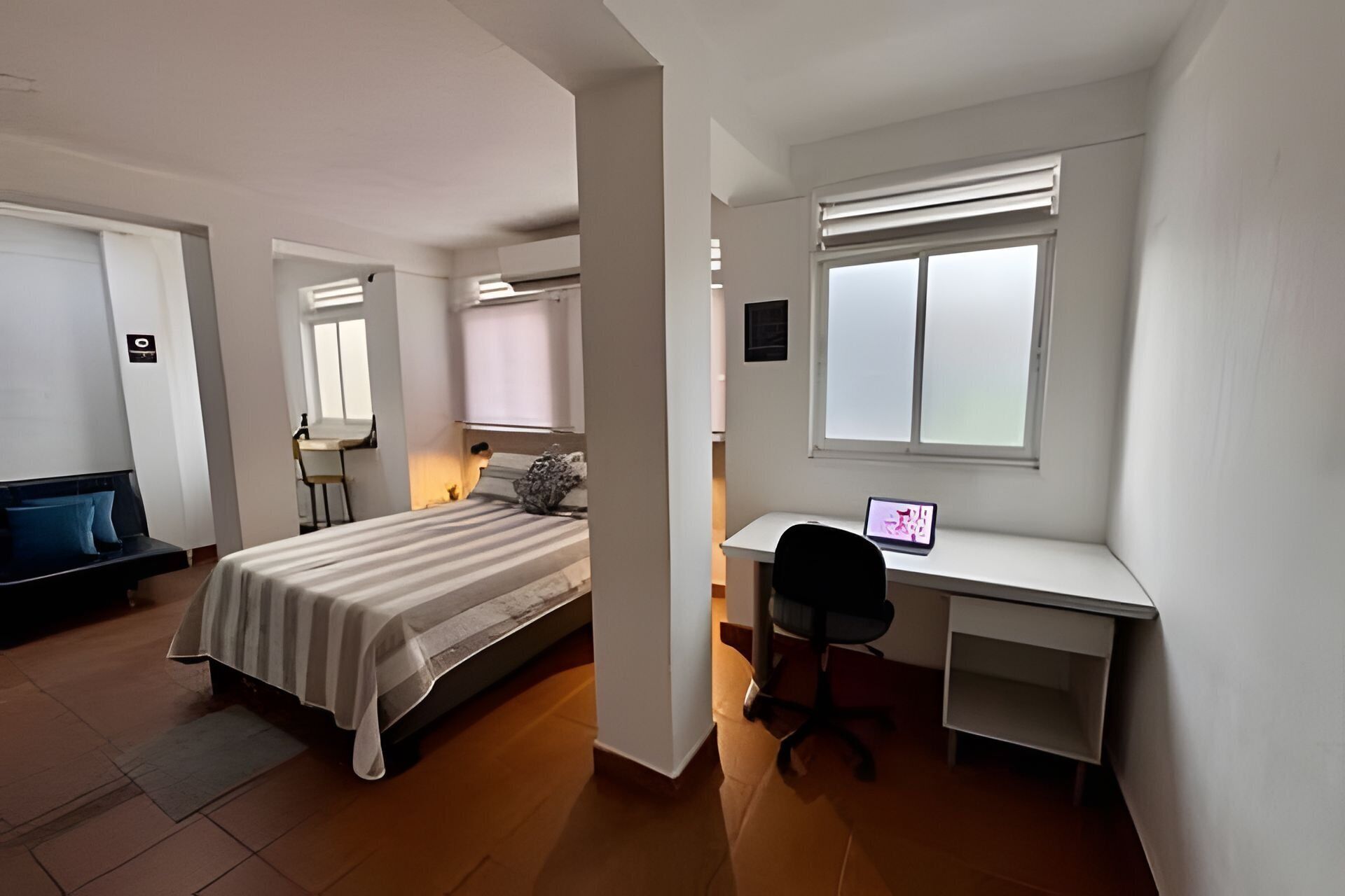 A bedroom with a bed, a desk, and a chair.