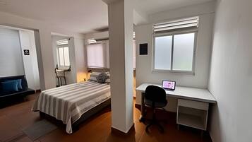 A bedroom with a bed, a desk, and a chair.