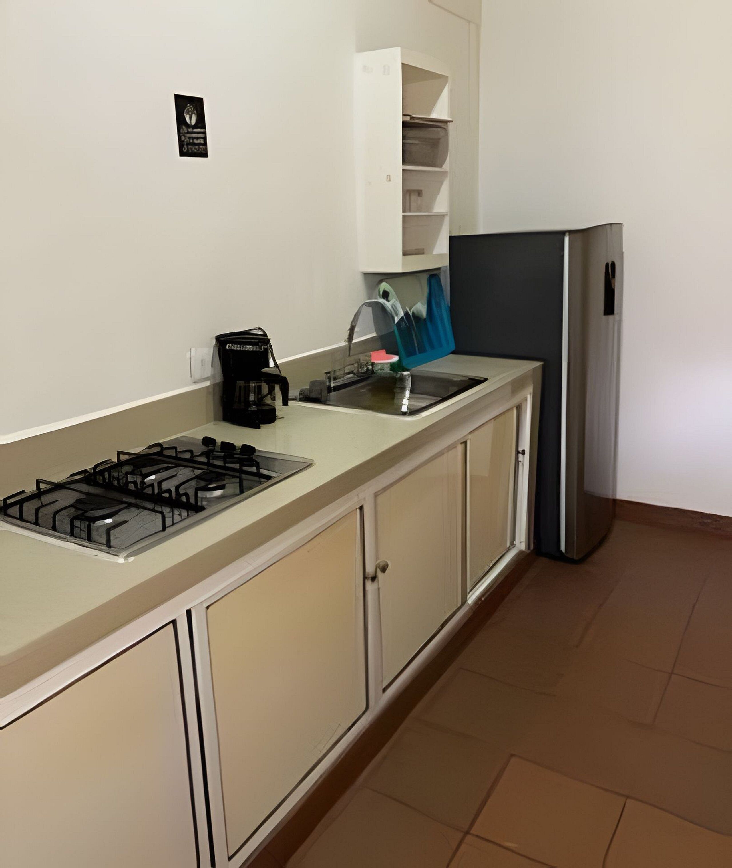 A compact kitchen with a gas stove, a coffee maker, and a refrigerator.