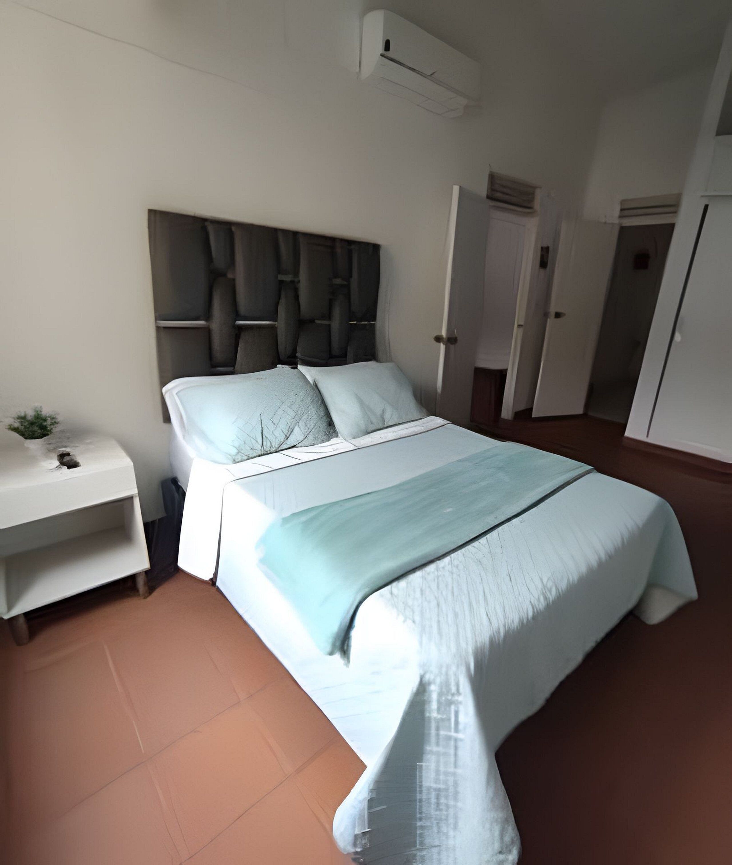 Une chambre à coucher comprenant un lit, une table de chevet et un appareil de climatisation.