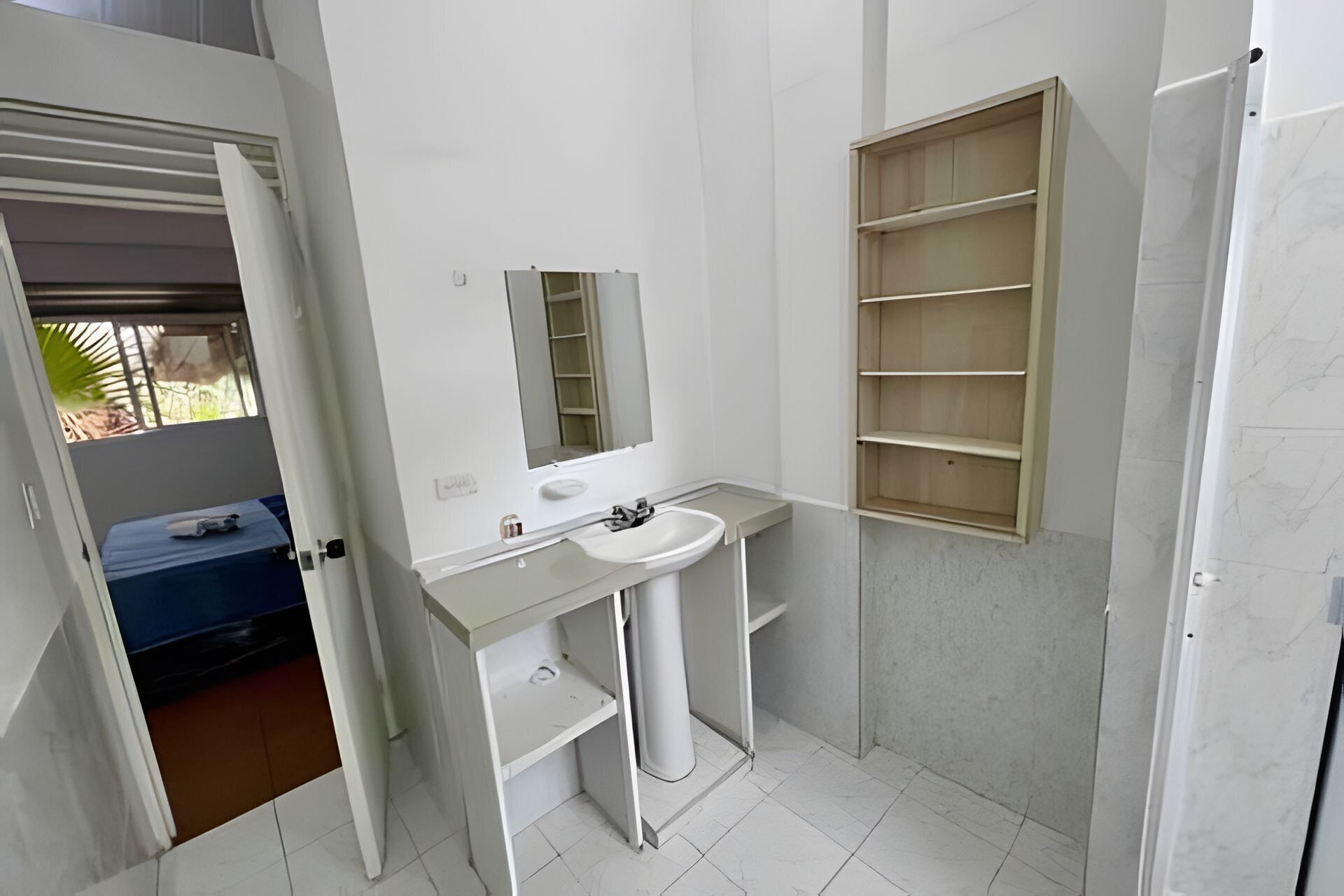 A bathroom with a white sink, mirror, and wooden shelves.