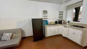 Una cocina compacta con armarios blancos, un refrigerador negro, un microondas y una estufa a gas.