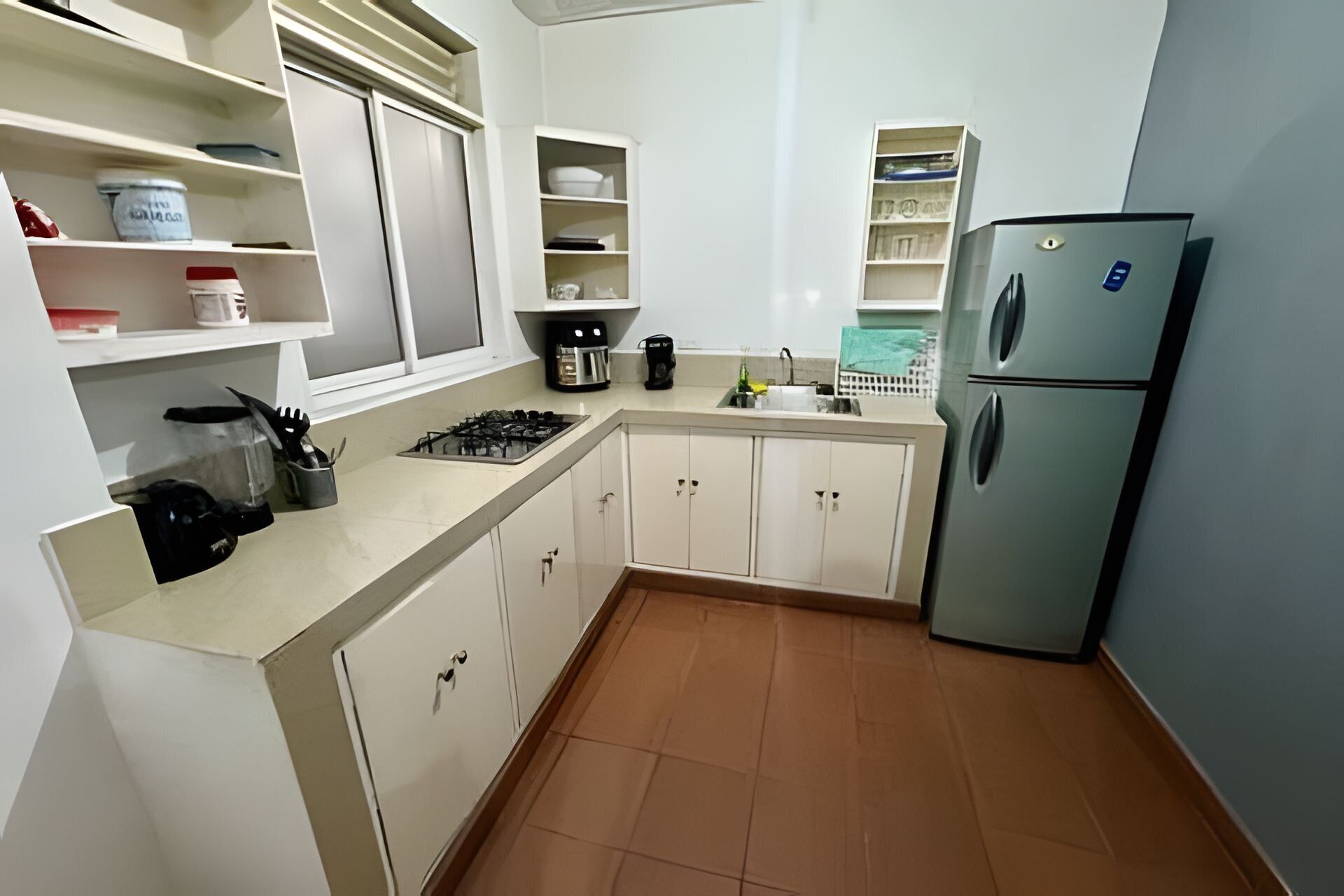 Une cuisine avec des meubles blancs, une cuisinière, un évier et un réfrigérateur.