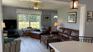 A living room with a television, leather sofas, a coffee table, and a dining table. - Abenaki Retreat on Matinicus Island (Matinicus)