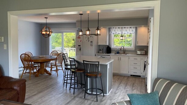 A kitchen with a dining area, bar stools, and a large island. - Abenaki Retreat on Matinicus Island (Matinicus)