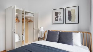 Un dormitorio con una cama, un armario y dos cuadros en la pared.