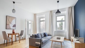 Una sala de estar moderna con un sofá gris, una mesa de centro de madera y un mueble para televisión.