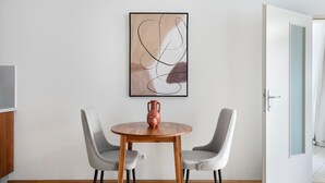Un comedor moderno con una mesa redonda de madera, dos sillas grises tapizadas y un jarrón decorativo.
