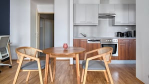 A compact kitchen with modern appliances, two wooden chairs, and a small table.