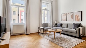 Ein modernes Wohnzimmer mit einer Couch, einem kleinen Tisch und einem Fernseher.