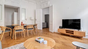 Ein geräumiges Wohnzimmer mit Essbereich, einem Fernseher und einem Bücherregal.