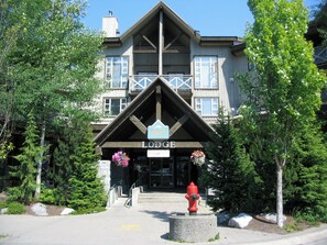 A lodge with a prominent entrance, a fire hydrant, and surrounding greenery.