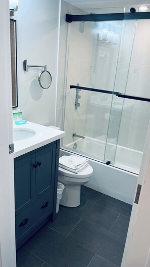 A bathroom with a glass-enclosed shower, a white sink, and dark blue cabinets. - Main Village • 1 Bedroom • Queen+2 Sofabeds • AC • Laundry • Parking • EV • Reno (Whistler)